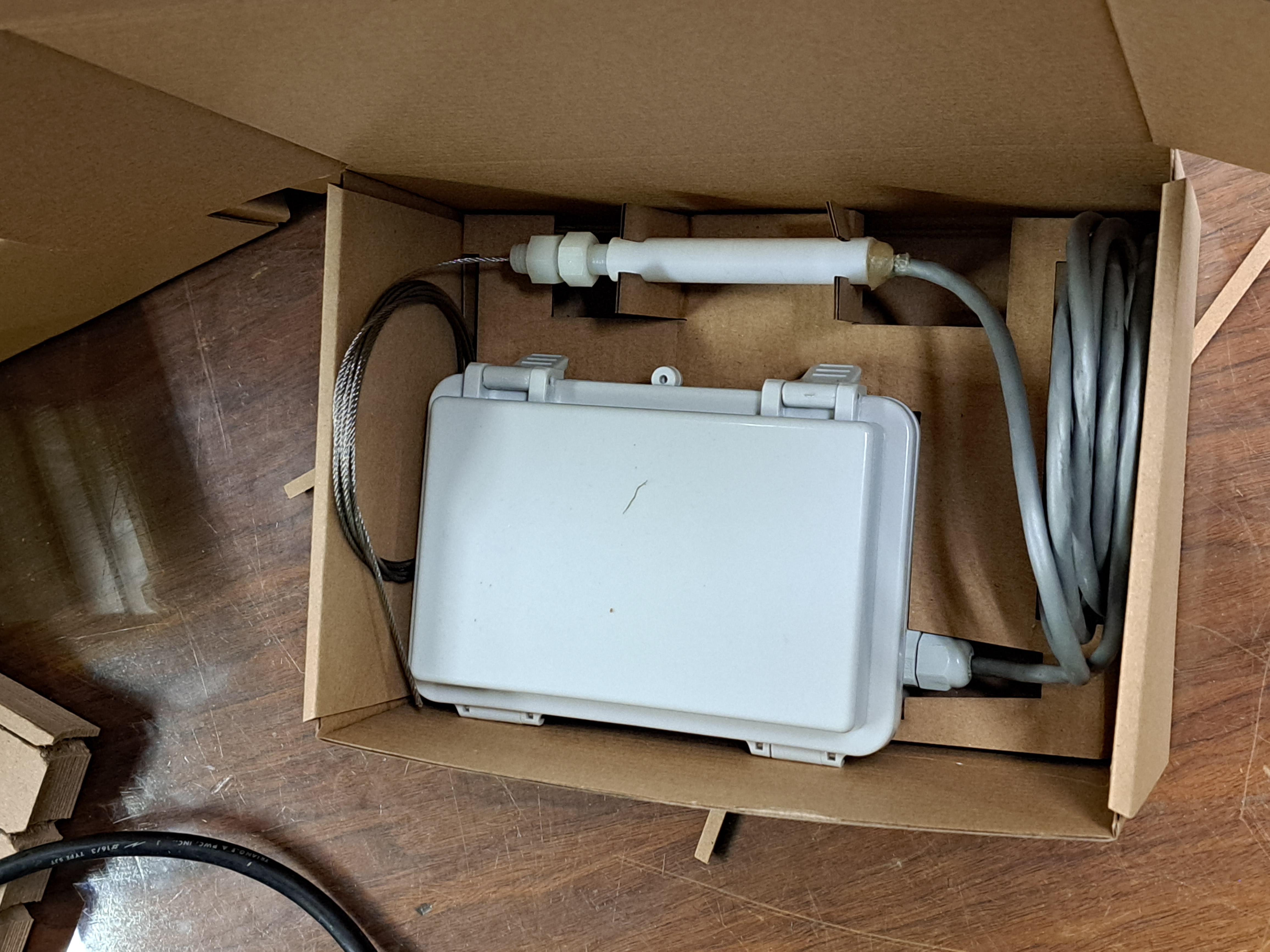 A well monitor device in a cardboard box.